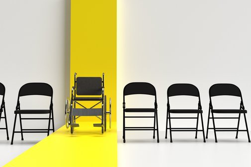 Inklusion in der Gesellschaft Klappstühle stehen in einer Reihe vor einer weißen Wand, in der Mitte ein Rollstuhl vor einem gelben Streifen, der sich über die Wand und den Fußboden zieht.