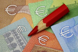 Euroscheine und ein roter Buntstift als Symbol fürs Sparen