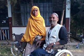 Ein älterer Mann sitzt im Rollstuhl, neben ihm steht eine Frau. Das Bild ist in Äthiopien aufgenommen, der Rollstuhl wurde über das Projekt "Konvoi der Hoffnung" gespendet. 