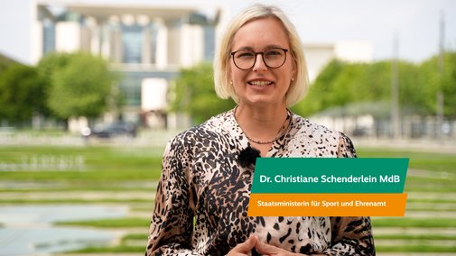 Dr. Christiane Schenderlein Christiane Schenderlein, Staatsministerin für Ehrenamt und Sport, spricht in die Kamera. Hinter ihr ist das Bundeskanzleramt zu sehen.