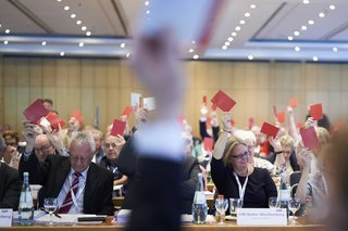 Blick in den Tagungssaal: Die Ordentlichen Delegierten des VdK-Bundesverbandstags 2023 in Berlin halten zur Abstimmung ihre roten Stimmkarten hoch.