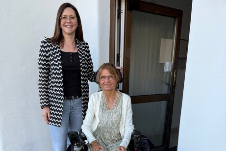 Wohnberatung beim VdK Arberland Manuela Ernst, im Rollstuhl, und Franziska Geiß stehen nebeneinander vor einer Tür mit elektrischem Türantrieb.