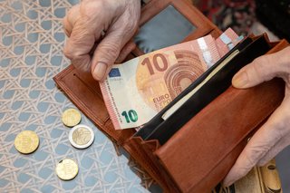 Ältere Preson hält einen Geldbeutel und 10 Euro Schein in der Hand 