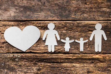 Familie Eine aus Papier ausgeschnittene Familie mit Vater, Mutter und zwei Kindern auf hölzernem Untergrund