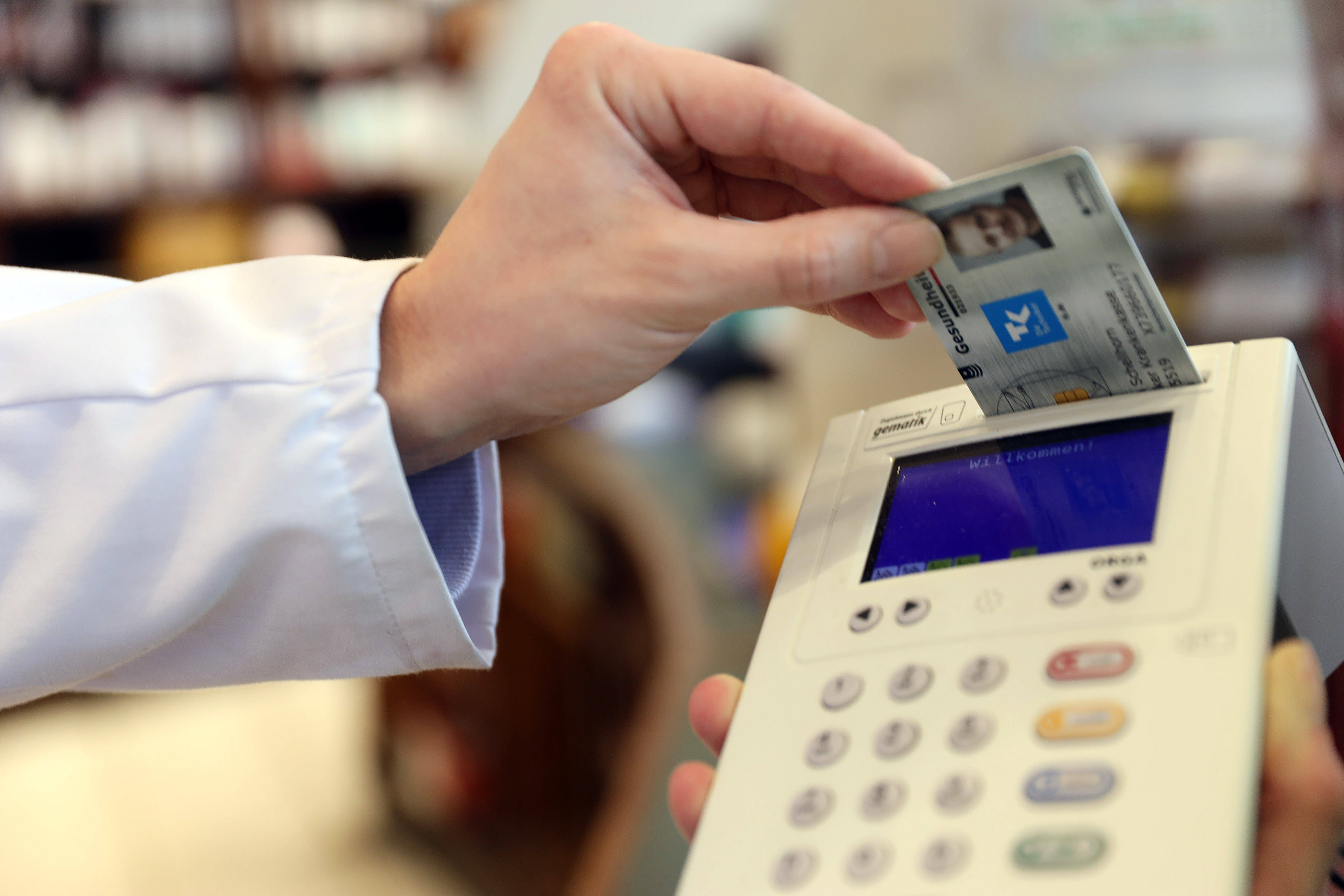Die Hand eines Apothekers beim Einlesen einer Versichertenkarte mit einem Gerät, um das darauf hinterlegte E-Rezept abzurufen. 