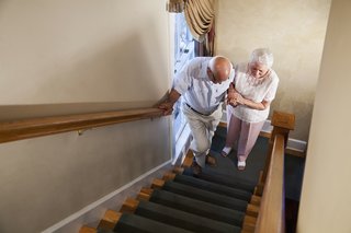 Ältere Frau die ihrem Ehemann hilft Treppen zu steigen