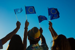 Mensche halten kleine Europaflaggen in den Himmel