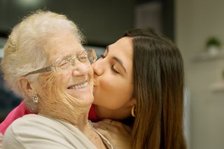 Enkelin küsst ihre Großmutter auf die Wange