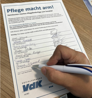 Hand mit Stift, die auf Unterschriftenformular unterschreibt