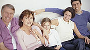 Symbolfoto: Eine Familie, bestehend aus Großeltern, Eltern und Enkelin, gemeinsam auf einer Couch