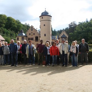 Das Bild zeigt das Wasserschloss Mespelbrunn mit einigen Teilnehmern des Herbstausfluges in 2023
