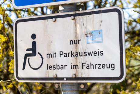 Behindertenparkplatz Ein Verkehrsschild an einem Behindertenparkplatz mit einem Rollstuhl-Symbol und dem Text "nur mit Parkausweis lesbar in Fahrzeug".