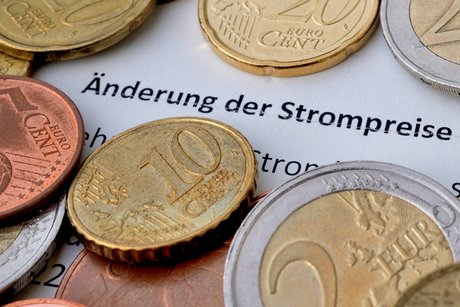 Ein Brief eines Energieversorgers, zu lesen ist "Änderung der Strompreise", darauf liegen Münzen