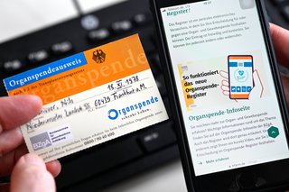 Die Internetseite www.organspende-register.de auf einem Smartphone und ein Organspendeausweis 