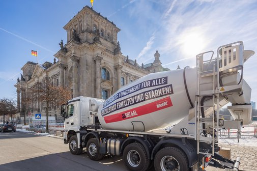 Ein großer Betonmischer mit dem Aufdruck "Ein stabiles Fundament für alle: Sozialstaat erhalten und stärken" steht vor dem Bundestag in Berlin. 