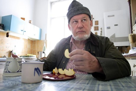 Rentner sitzt am Küchentisch und isst.