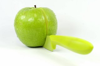 Symbolfoto für gerechtes Teilen: Ein grüner Apfel wird mit einem grünen Messer in zwei gleich große Hälften geteilt.