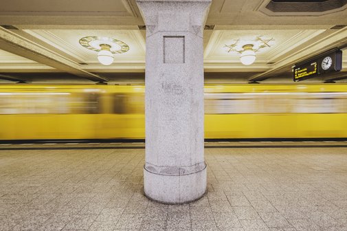 Mobilität Die U-Bahnlinie 3 verkehrt am Ruedesheimer Platz in Wilmersdorf in Berlin. Man sieht die U-Bahn verschwommen, sie fährt gerade ein. Ein Stützpfeiler teilt das Foto in zwei Hälften.