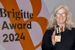 Christina Clemm beim Brigitte Award, sie hält ihre Auszeichnung hoch und lächelt.