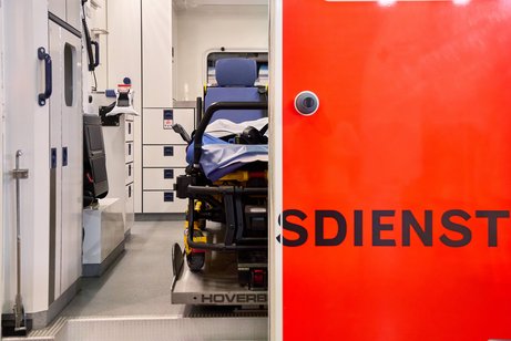 Rettungsdienst Blick in einen Rettungswagen, die linke Tür ist geöffnet und gewährt den Blick ins Innere, die rechte Tür ist geschlossen, so dass nur die Buchstaben "sdienst" des Wortes Rettungsdienst zu lesen sind.