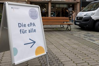 Ein Aufsteller mit einem Poster, auf dem steht "Die ePA für alle" und einem Pfeil nach rechts