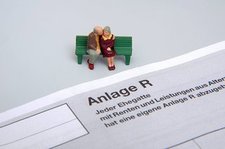 Steuererklärung der Renteneinkünfte: Figuren eines Rentnerehepaares sitzen auf einer Bank vor dem Formular - Anlage R - 