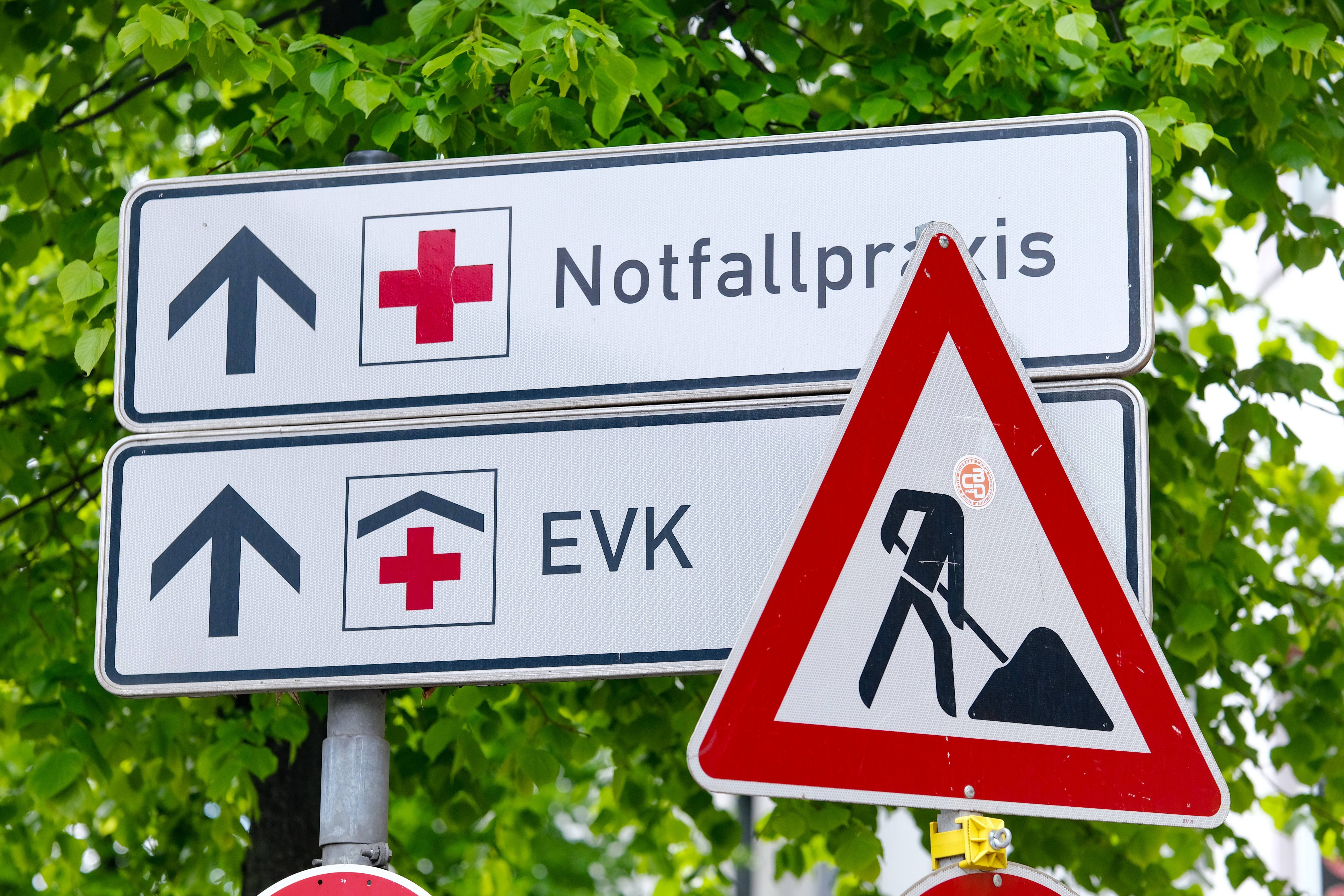 Die Bildmontage zeigt zwei Wegweiser an einem Krankenhaus, auf denen steht "EVK" und "Notfallpraxis". Daneben ein Baustlellenschild.