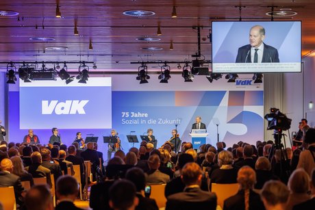 Blick in den Veranstaltungssaal beim VdK-Festakt, vorne auf der Bühne steht Olaf Scholz am Rednerpult.