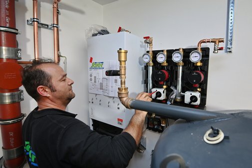Gebäudemodernisierungsgesetz Ein Heizungsmonteur arbeitet an einer Heizungsanlage.
