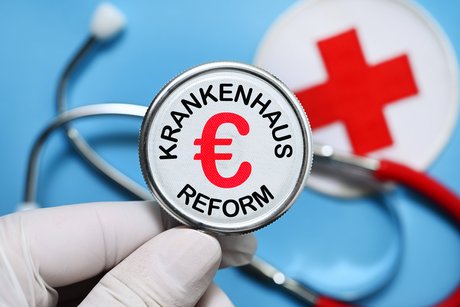 Die Bildmontage zeigt eine Hand mit medizinischem Handschuh, die eine Stethoskop hält, in dessen Mitte das Wort "Krankenhausreform" und ein Euro-Zeichen stehen. 