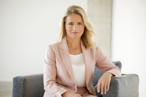 Verena Bentele Das Foto zeigt Verena Bentele, sie sitzt in einem grauen Sessel und hat einen Arm auf der Lehne abgelegt