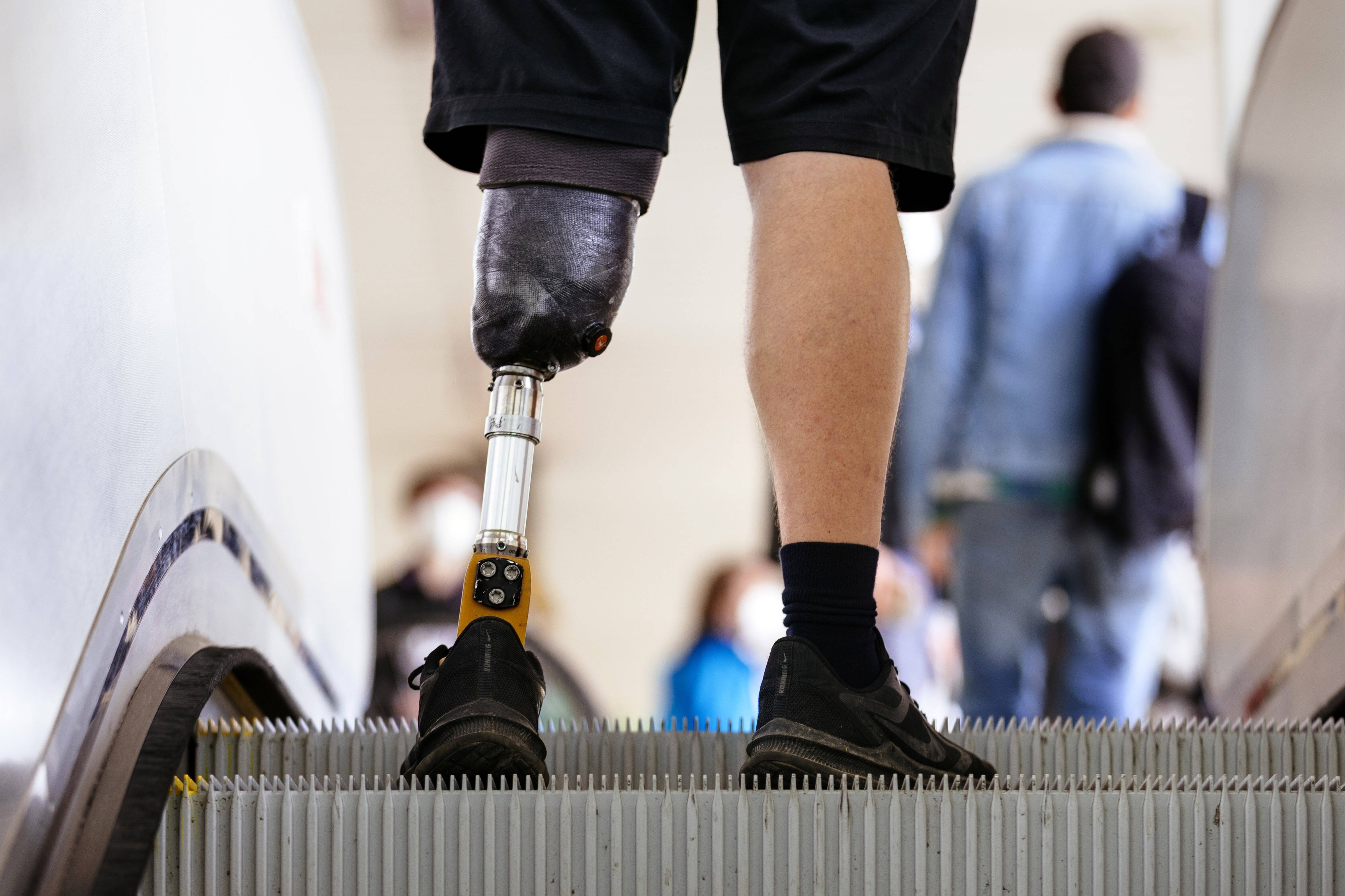 Schwerbehinderung ab einem GdB von 50 Ein Mann mit einer Beinprothese fährt Rolltreppe. Man sieht nur seine Füße und Waden, an einem Bein hat er eine Unterschenkelprothese.
