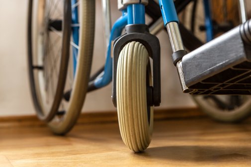 Pflegeheim mit Rollstuhl Nahaufnahme eines Rollstuhls: Man sieht ein großes und ein kleines Rad sowie einen Teil des Fußteils