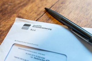 Ein Brief mit Absender Deutsche Rentenversicherung liegt auf einem Tisch, darauf ein Kugelschreiber
