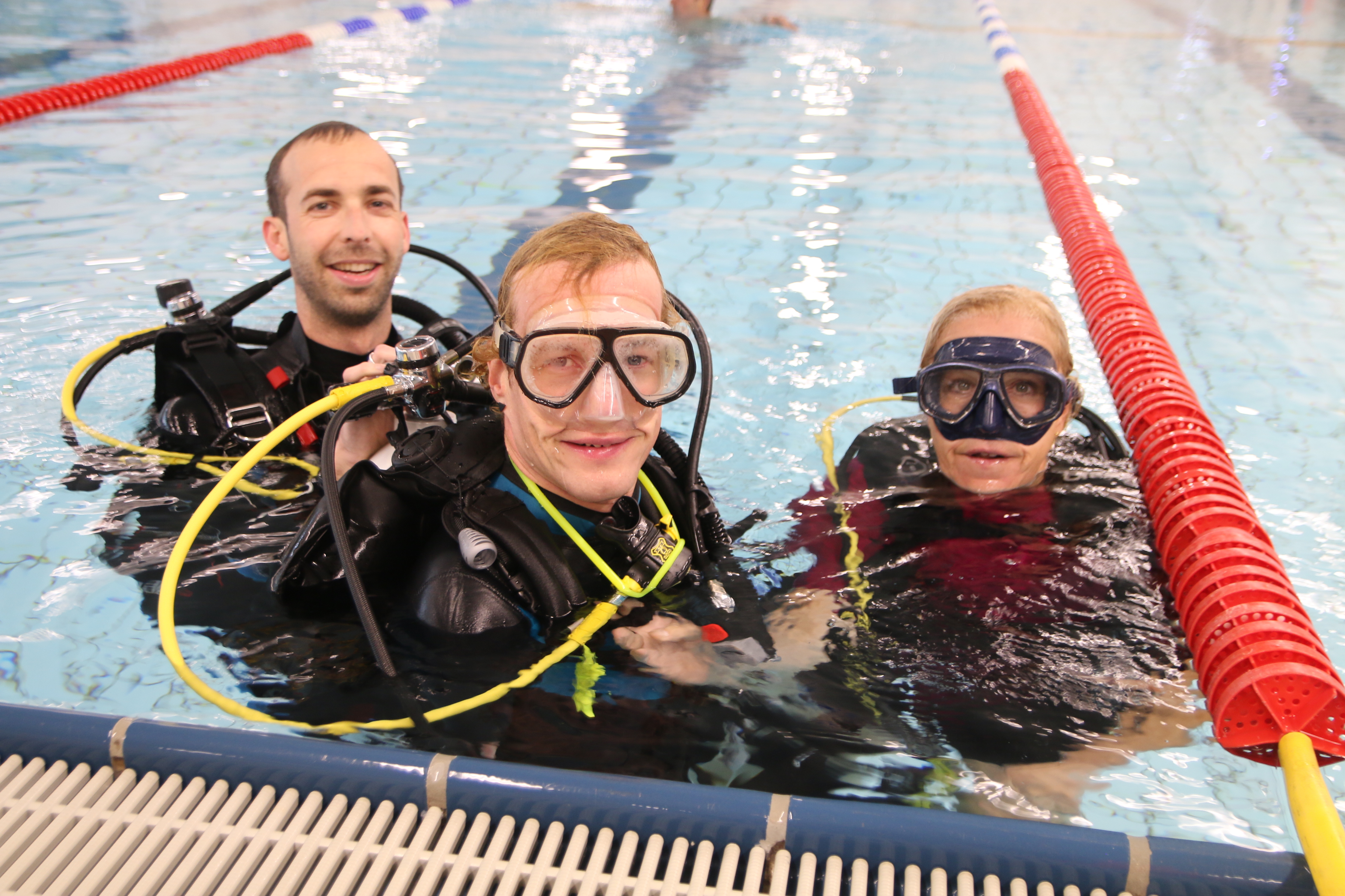  Étienne Galvani, Janis McDavid und Carola Zidan gemeinsam im Schwimmbecken, sie tragen die Tauch-Ausrüstung.