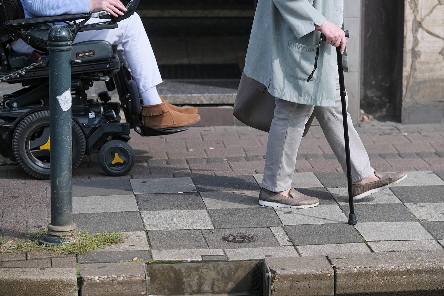 Im Rollstuhl sitzende Person und Mensch mit Gehstock