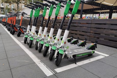 E-Roller stehen nebeneinander auf dem Bürgersteig